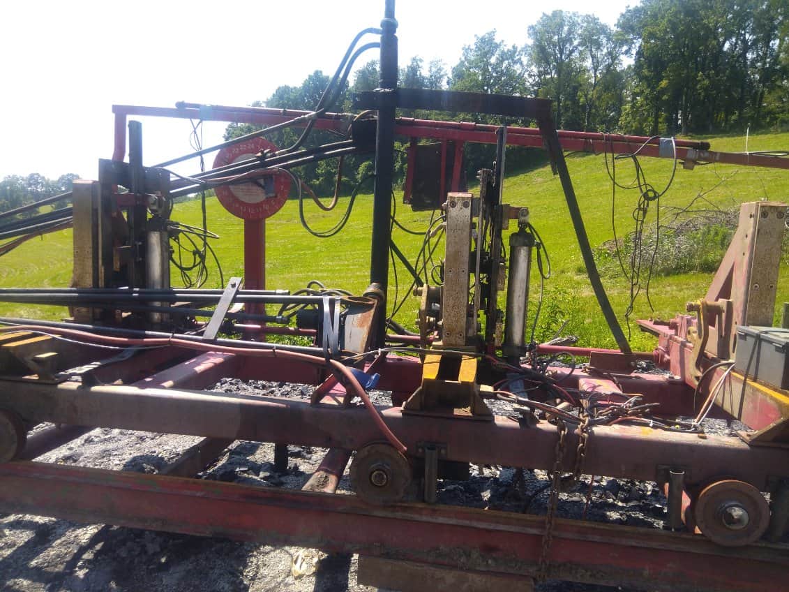 Heavy-duty industrial sawmill equipment with hydraulic components and conveyor system.