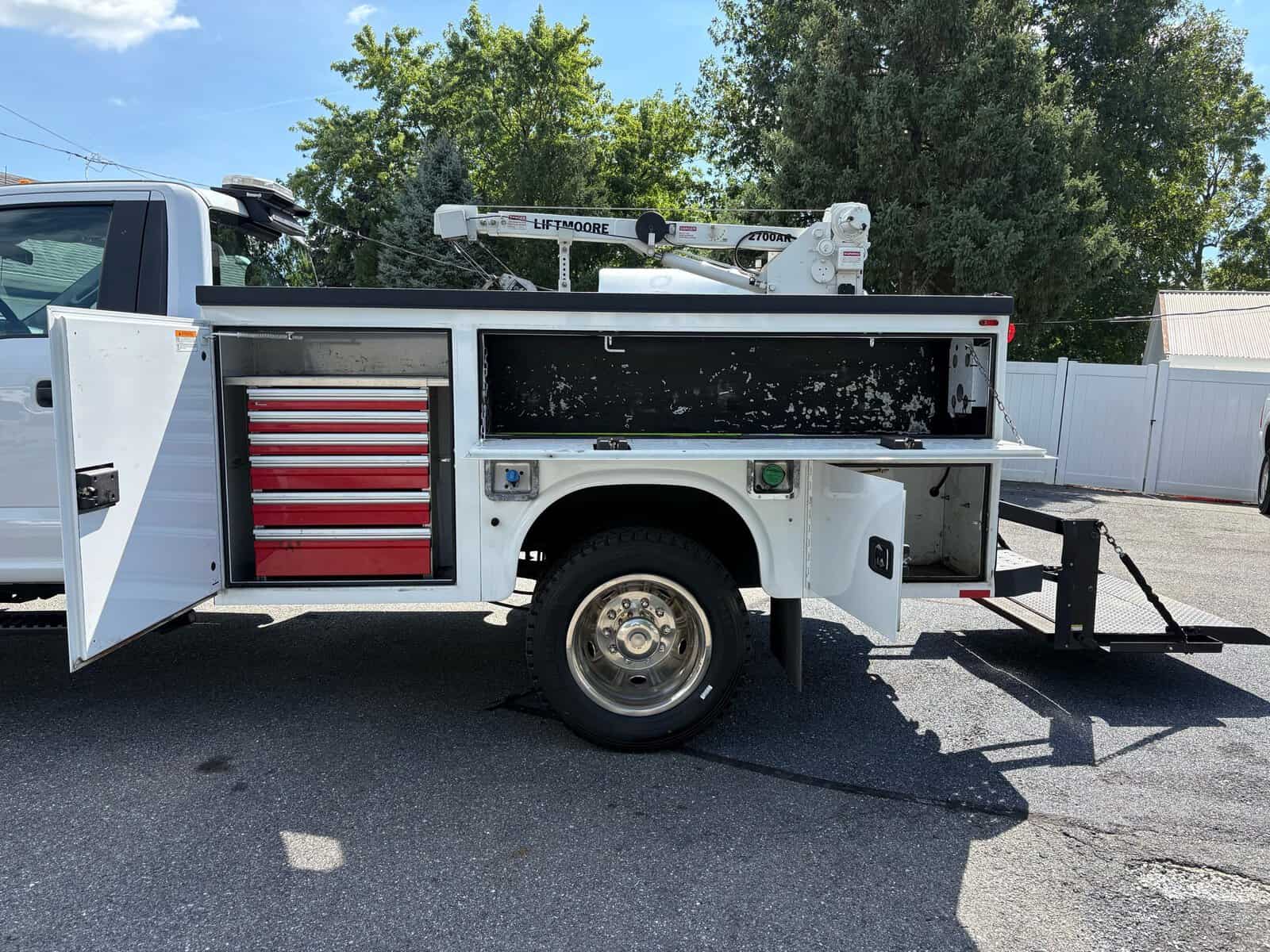 10946 - 2018 Ford F-550 Chassis - 005 Service truck with storage compartments and hydraulic lift, white with red drawers, parked outdoors.