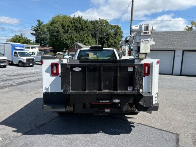Service truck with bucket lift and equipment storage at the rear, parked on a paved lot.