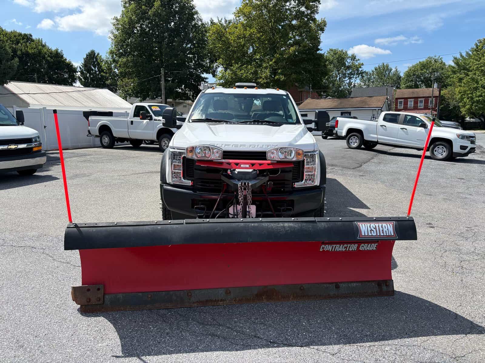 10946 - 2018 Ford F-550 Chassis - 013 White snow plow truck with red blade and black snow deflector in parking lot.