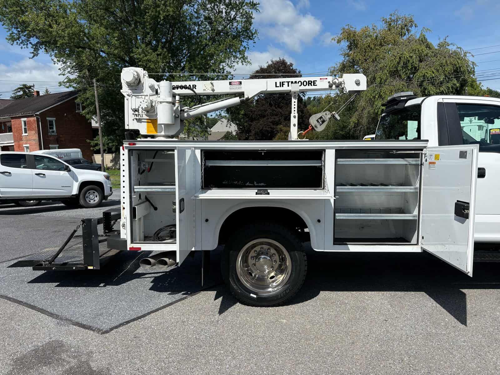 10946 - 2018 Ford F-550 Chassis - 016 White bucket truck with lift arm and storage compartments on a city street.