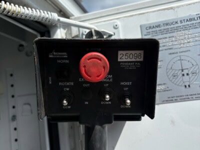 Crane truck stability control panel with red emergency stop button and control switches.