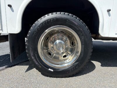 Heavy-duty truck tire with chrome rim on a white vehicle.