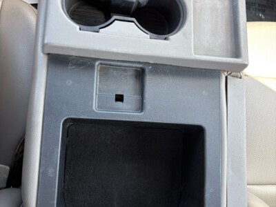 Center console with cup holders and storage compartment in a vehicle interior.