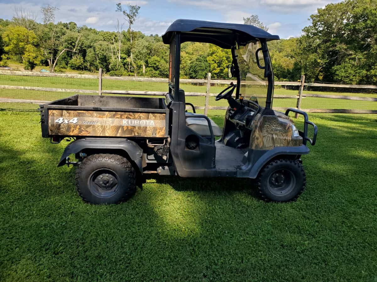 Kubota RTV900 4x4 utility vehicle with cargo bed and canopy, outdoor setting.