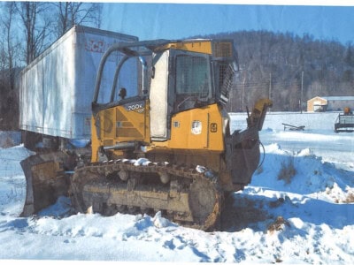John Deere 700K tracked crawler dozer with blade in snowy landscape, winter conditions.