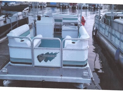 Suncruiser pontoon boat with white seating and railing at marina.