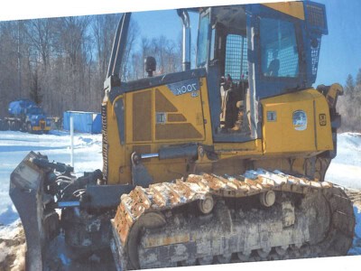 Yellow John Deere 850K crawler dozer with blade in snowy landscape, cab, and tracks.