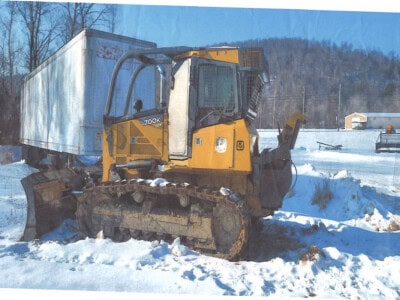 John Deere 700K tracked bulldozer with cab and blade in snowy landscape.