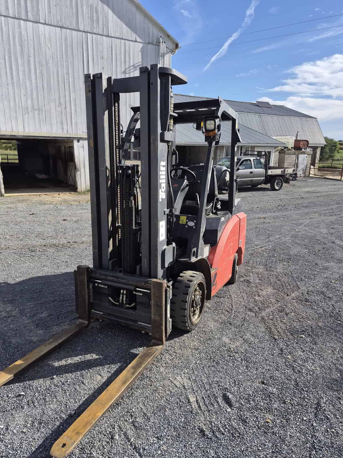 20260925_091427 (1) Red and black Toyota forklift with extended forks on gravel yard.