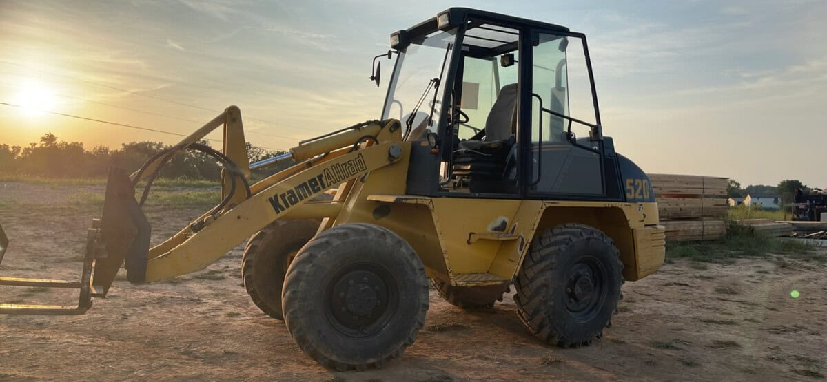 2000 Kramer-Allrad 520 compact loader with cab and front bucket at sunset.