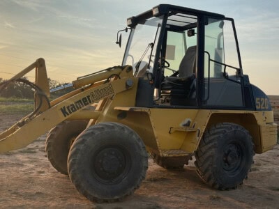 2000 Kramer-Allrad 520 compact loader with cab and front bucket at sunset.