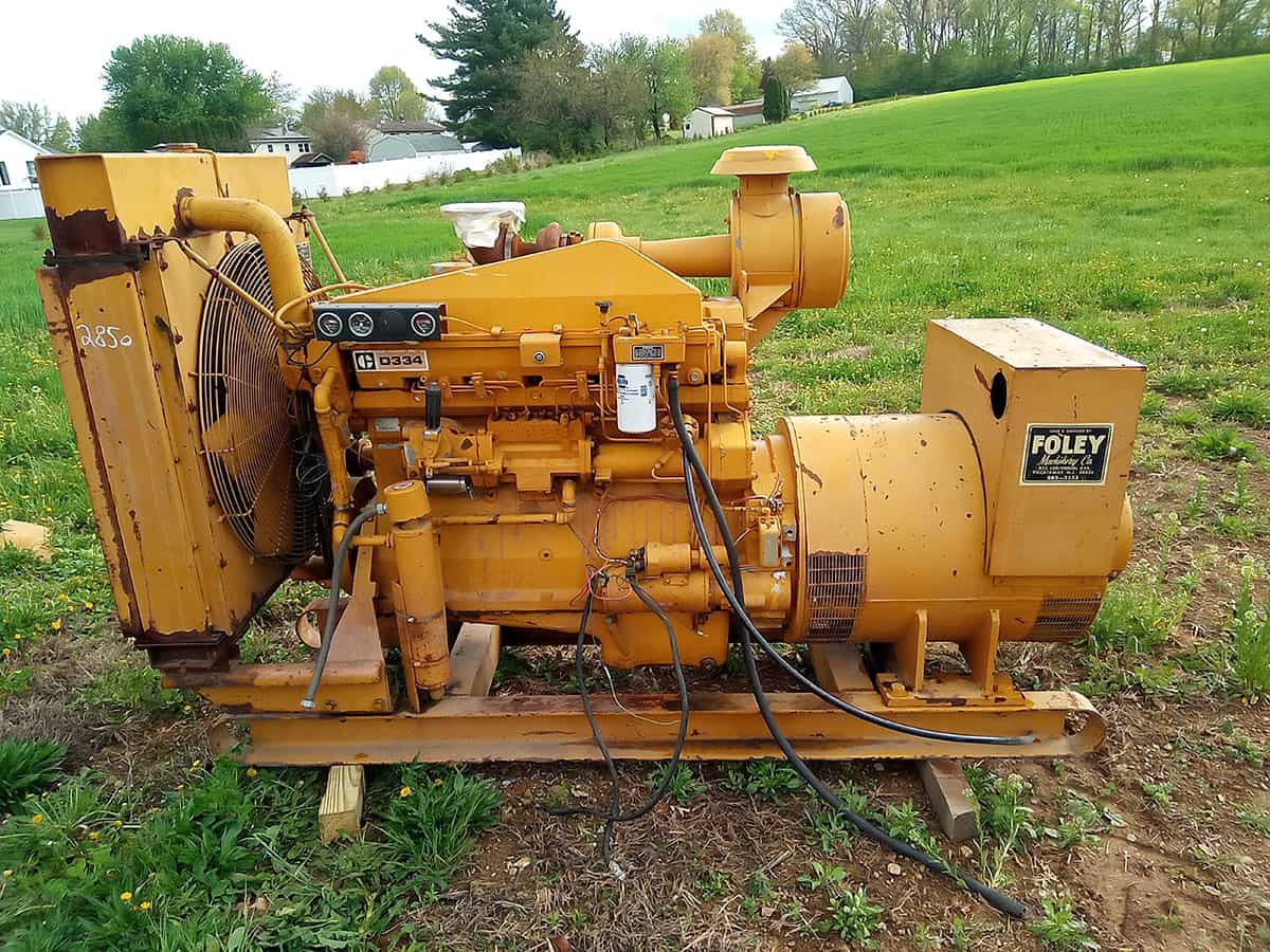 Cat Genset 1 Caterpillar D334 industrial generator with yellow exterior and cooling fan, on grassy field.