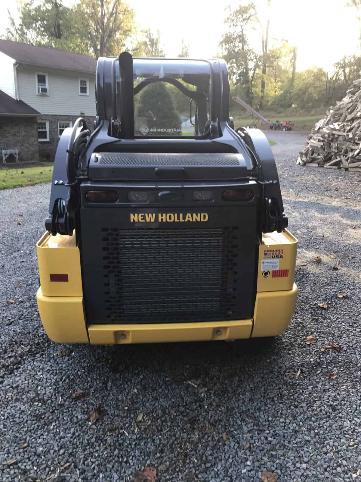 IMG_0739 (1) New Holland L320 compact loader with enclosed cab and yellow body, rear view in outdoor setting.