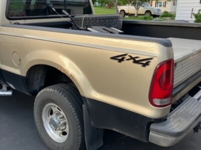 2004 Ford F-150 4x4 pickup truck with beige body and black accents, parked outdoors.