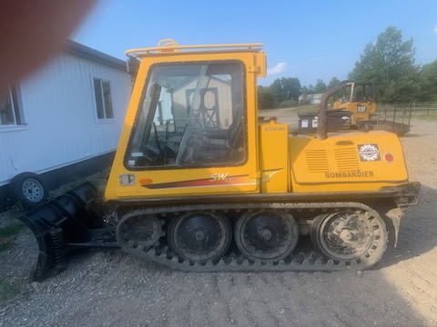 Yellow Bomag BW80AD-4 compact track loader with cab and rubber tracks on gravel surface.