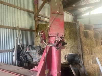Red New Holland 782 hay baler with pickup and hydraulic components in barn.