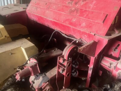 Red farm machinery with large cover and visible mechanical parts.