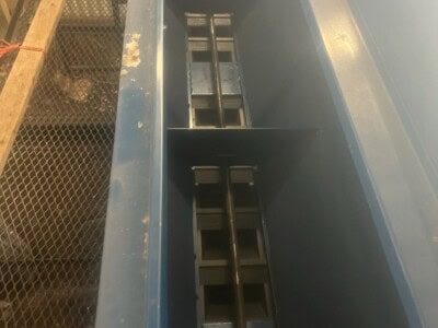 Blue loader bucket attachment with hydraulic linkage for construction equipment.