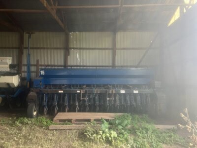 2015 blue agricultural seeder with multiple seed dispensers in a barn.