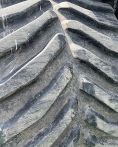 Close-up of large tractor tire with deep, rugged treads for agricultural use.