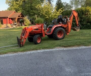 Kubota L2501 compact tractor with backhoe attachment on grassy lawn.