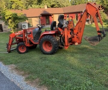 Kubota B6200 compact tractor with backhoe attachment on grassy lawn.