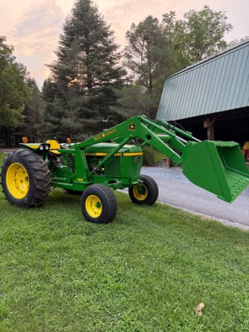 Green John Deere 2440 compact tractor with front loader and yellow wheels on grassy area.