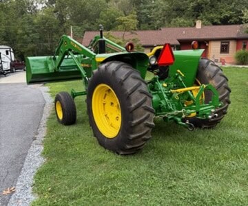 John Deere 2440 tractor with front loader and rear ballast box on grassy lawn.