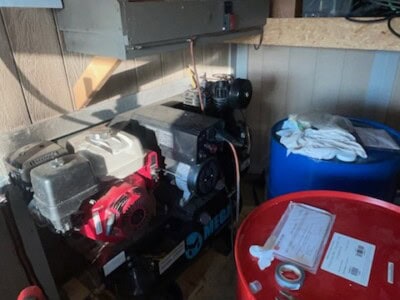 Portable spray foam insulation system with compressor and hoses in a workshop.