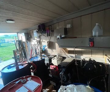 Indoor storage with insulation equipment, tools, and supplies on shelves and workbenches.