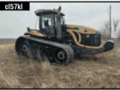 John Deere 8R tractor with tracks and enclosed cab in a field.