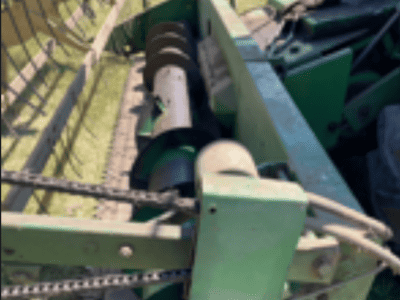 Green agricultural equipment with reel and cutting mechanism in a field.