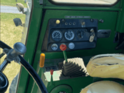 Close-up of tractor control panel with gauges and levers inside green cab.