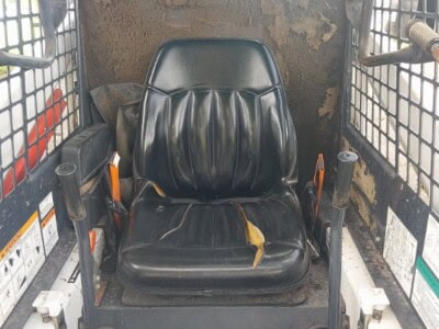 Bobcat 553 skid steer loader operator seat with control levers and protective cage.
