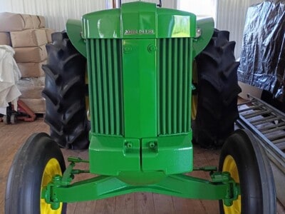 John Deere 6200 tractor with front grille and large rear tires in indoor storage.