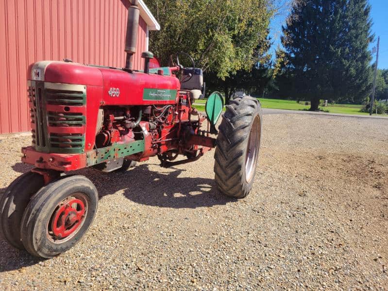 image000004 (4) Red Farmall 450 tractor with large rear tires and enclosed cab on gravel surface.