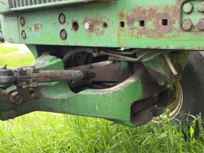 Close-up of the front of a green 1972 John Deere 4620 tractor showing the radiator and front axle.