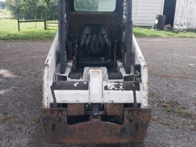 Bobcat 553 compact track loader with enclosed cab and visible wear on the bucket.