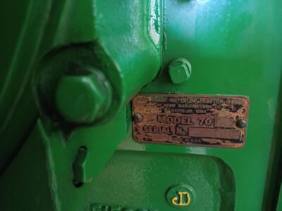 Close-up of green John Deere equipment with model and serial number plate visible.