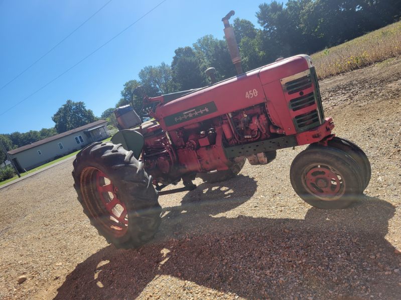 image000006 (3) Red Farmall 450 tractor with large rear tires and enclosed cab on gravel lot.