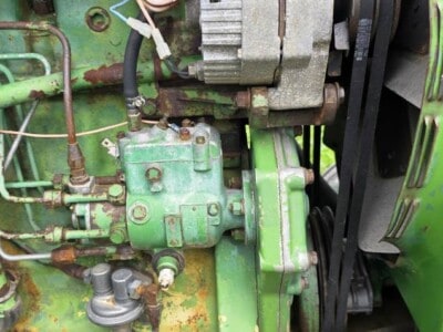 Close-up of green tractor engine with visible wiring and mechanical components.