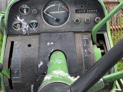 John Deere 4620 tractor dashboard with gauges and controls, green exterior, and worn steering wheel.