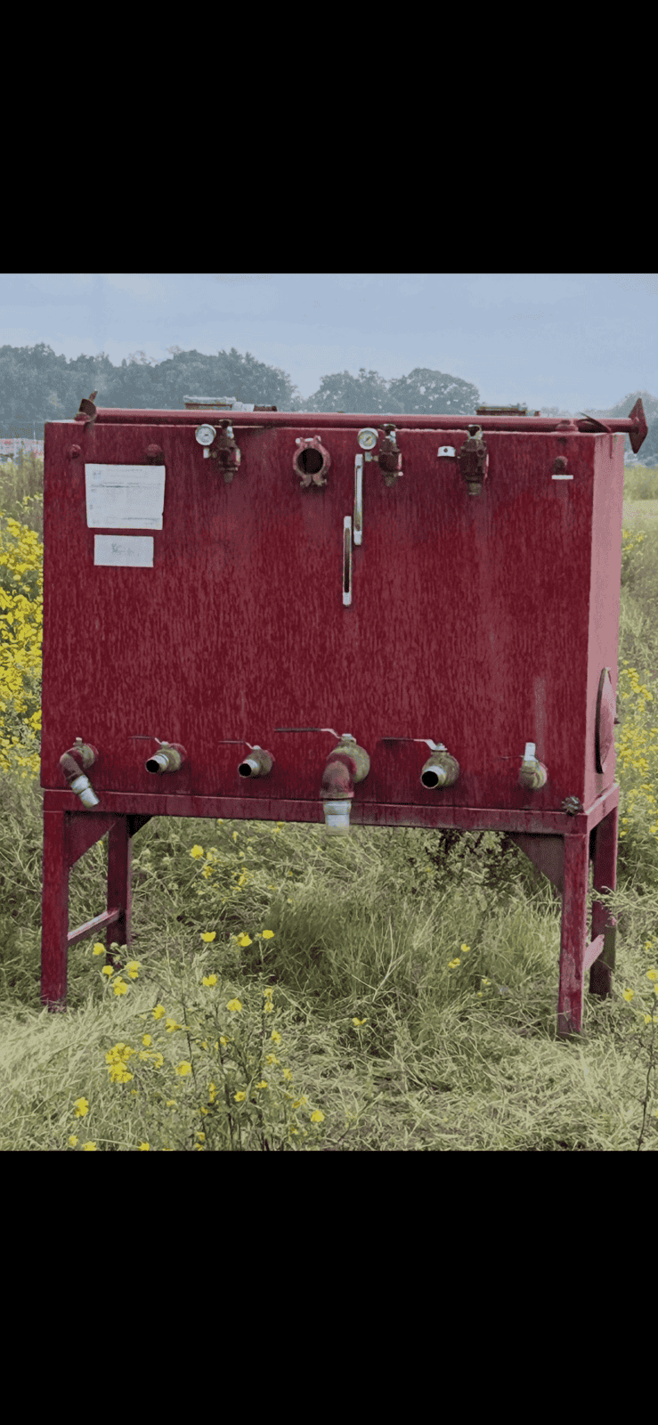 image1 (1) Red industrial tank with multiple pipes and valves in an outdoor field.