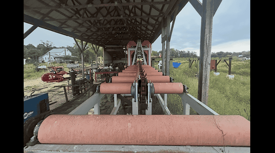 Heavy-duty Sharp Chain Scragg Mill with large rollers and conveyor system under a metal roof.