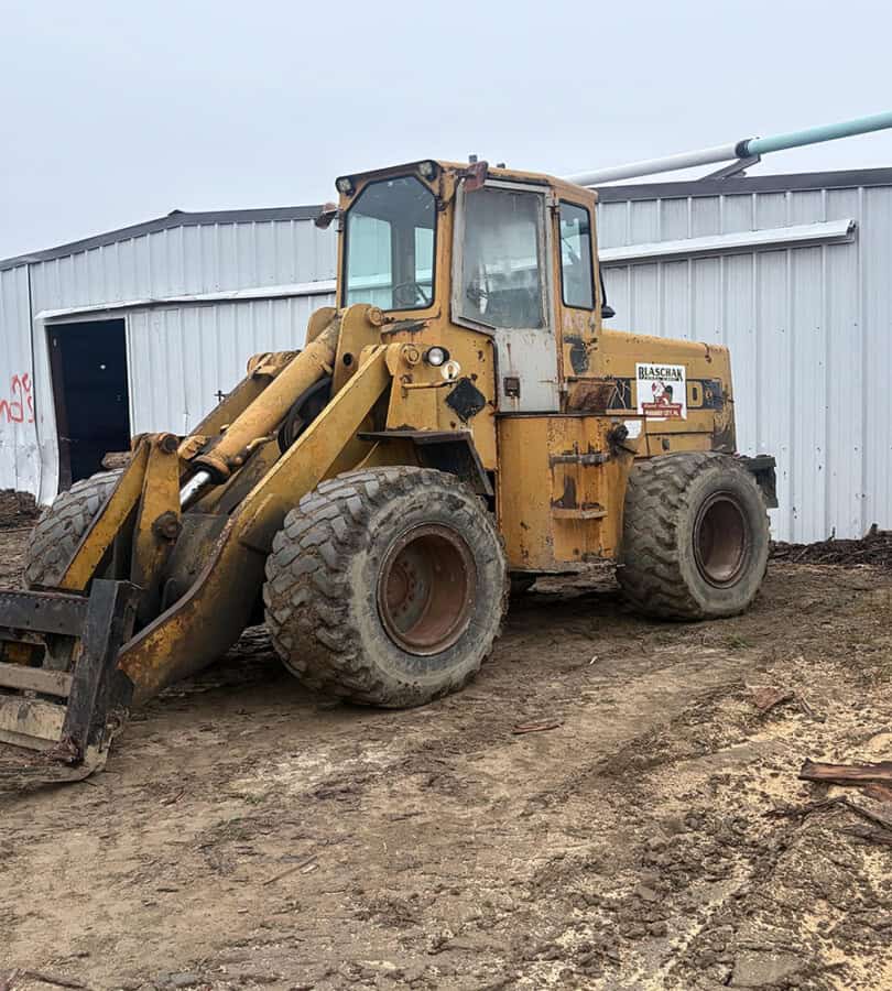 Yellow Ford A64 wheel loader with enclosed cab and large tires on dirt ground.