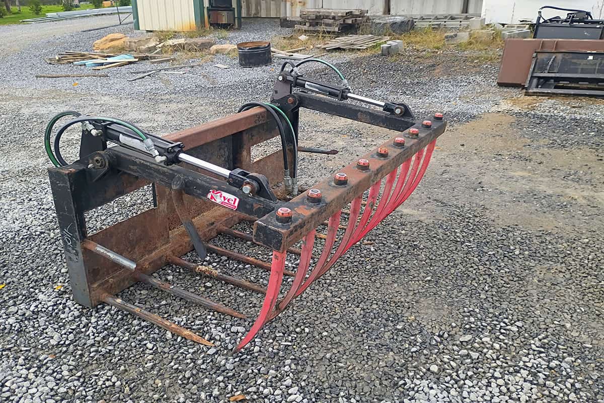 Heavy-duty Rake Attachment for Skid Steer Heavy-duty skid steer rake attachment with hydraulic controls and tines for land clearing and debris removal.