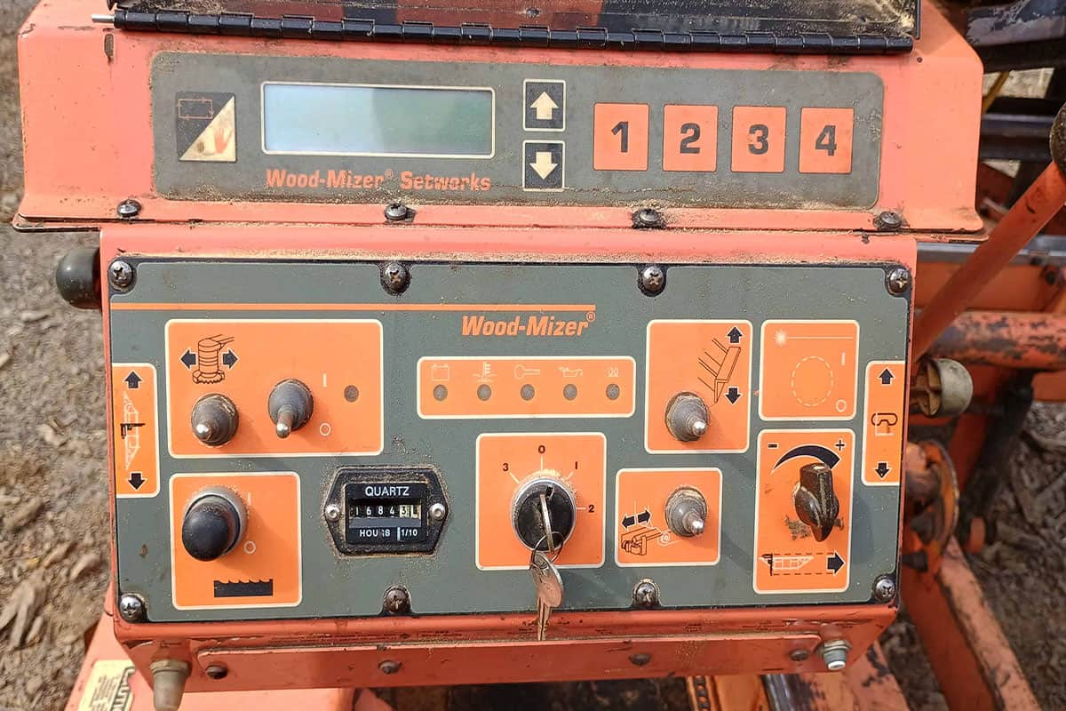 1000010692 (1) copy Wood-Mizer hydraulic sawmill control panel with orange and black interface and numbered buttons.