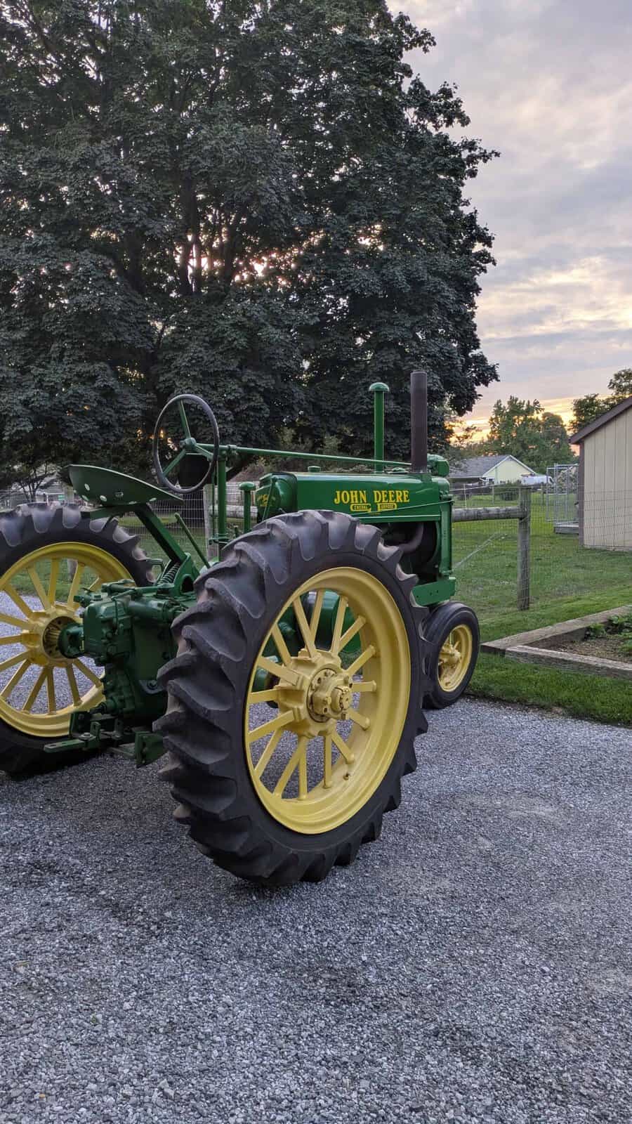 4452 (1) 1938 John Deere A tractor with green body and yellow wheels on gravel surface at sunset.
