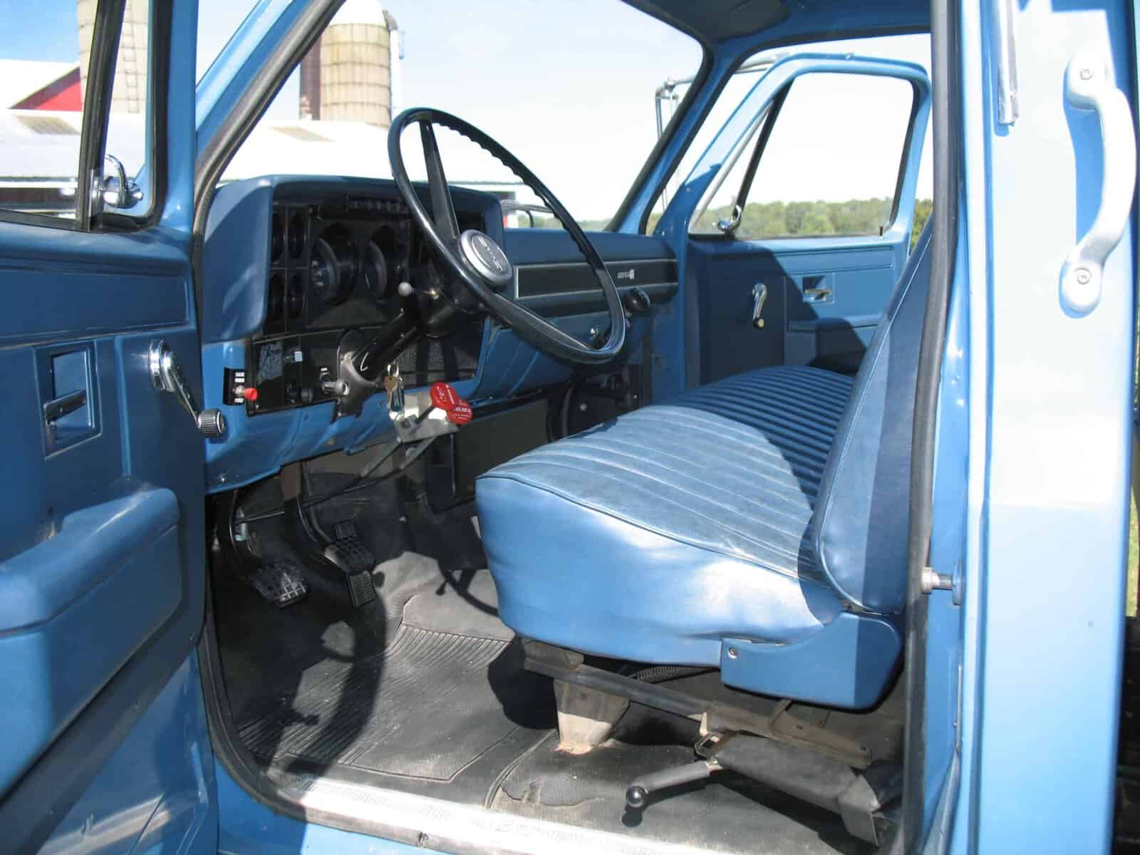 1985 GMC C7000 cab interior and seating Blue 1985 GMC C7000 grain truck cab interior with bench seat and steering wheel.